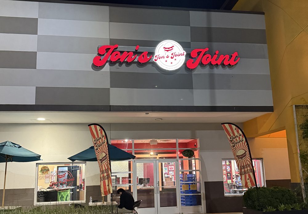 The Jon's Joint storefront on Richmond Highway in Alexandria at night, sign lit